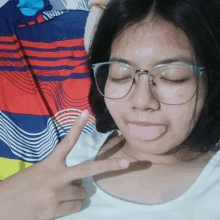 a girl wearing glasses is making a peace sign with her fingers