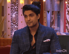 a man in a suit is sitting on a couch with ankit gif written on the bottom right