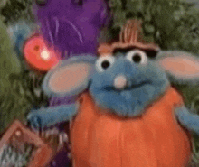 a close up of a stuffed animal wearing a hat and a pumpkin costume .