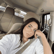 a woman wearing a white shirt is sitting in the back seat of a vehicle