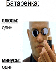 a man wearing sunglasses is holding a battery in front of his face