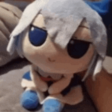 a stuffed animal with white hair and blue eyes is sitting on a person 's lap .