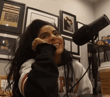 a woman sitting in front of a microphone wearing a sweatshirt with the letter p on the front