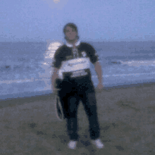 a man is standing on a beach holding a tennis racket and a bag