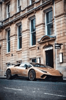 a gold lamborghini huracan is parked in front of a large building .