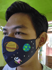 a young man wearing a face mask with planets and stars on it