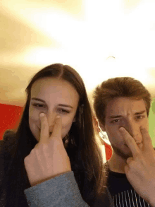 a man and a woman are covering their nose with their fingers