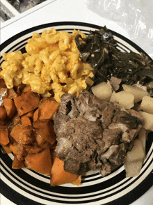 a plate of food includes macaroni and cheese collard greens potatoes and meat