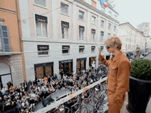 a man stands on a balcony in front of a building that says damiani on it