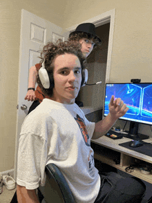 a man wearing headphones sits in front of a computer screen