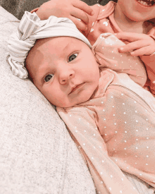 a baby wearing a headband and a pink polka dot outfit