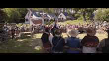 a group of people standing in front of a fence with a house in the background and a flag on it