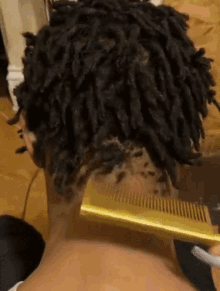 a person with dreadlocks is combing their hair with a comb