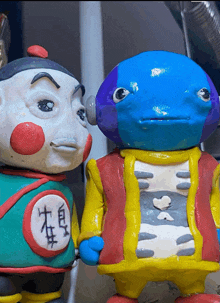 two clay figures with chinese writing on their shirts