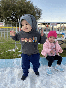 a boy and a girl are standing in the snow in front of a national sign