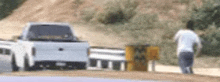 a man is walking down a dirt road next to a truck .