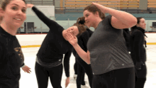 a group of women are standing on an ice rink and one of them is wearing a gray shirt with the letter t on it