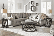 a living room with a gray sectional couch , two end tables , and a coffee table .