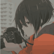 a girl with short black hair is holding a camera in her hands