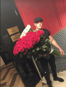 a man holding a large bouquet of red roses