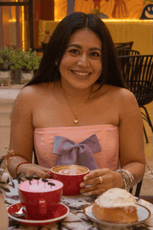 a woman sits at a table holding a cup of coffee and a piece of cake