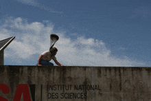 a man is sitting on a wall with the words institut national des sciences on it