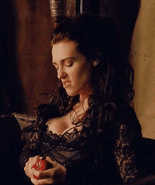 a woman in a black dress is holding a red apple in her hands