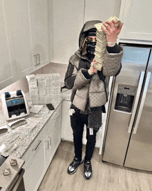 a man holding a stack of money in front of a refrigerator