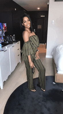 a woman in a striped jumpsuit is standing in a hotel room