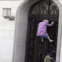 an elderly woman in a purple coat is climbing up a door