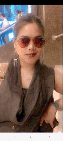 a woman wearing sunglasses and earrings is taking a selfie .