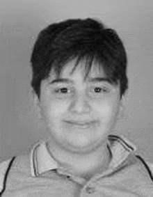 a black and white photo of a young boy wearing a polo shirt and smiling .