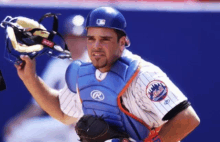 a man wearing a mets jersey holds his helmet