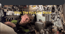 a man is laying in a machine with the words shut the fuck up mate