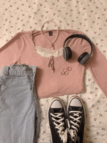 a pair of black converse shoes sit next to a pink shirt