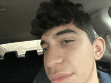 a young man with curly hair is taking a selfie in a car