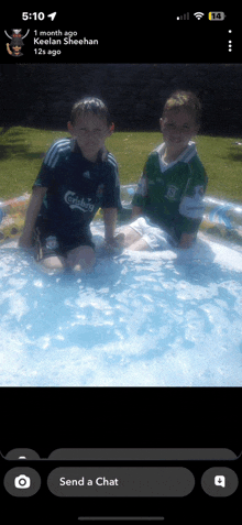 two boys in carlsberg shirts are sitting in a pool of water