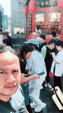 a man taking a selfie in front of a store with a sign that says ' xmx ' on it