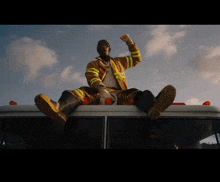 a man in a fireman 's uniform is sitting on top of an ambulance