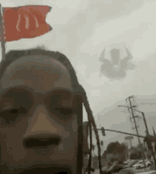 a man with dreadlocks is taking a selfie with a mcdonald 's flag flying in the background .