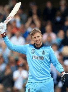 a man wearing a england jersey holds up his bat