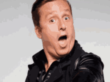 a man in a black jacket is making a surprised face with his mouth open