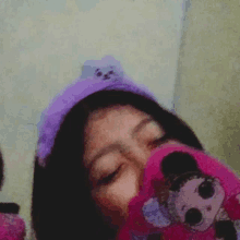 a girl wearing a purple headband is holding a stuffed animal