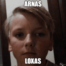 a close up of a young boy 's face with the words arnas loxas written on it