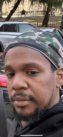 a man with a beard wearing a camouflage headband looks at the camera