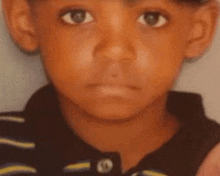 a close up of a young boy 's face in a black and yellow striped shirt .