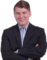 a man in a suit with his arms crossed smiles at the camera