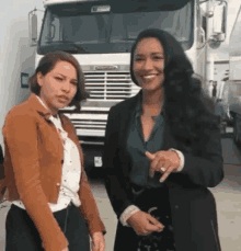 a couple of women are standing next to each other in front of a truck .