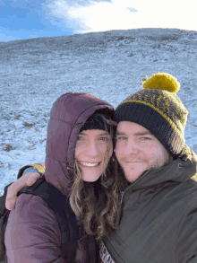 a man and a woman are posing for a picture in front of a snowy mountain