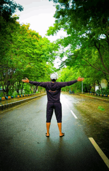 a man standing on a road with his arms outstretched wearing a sweatshirt that says ' freedom '